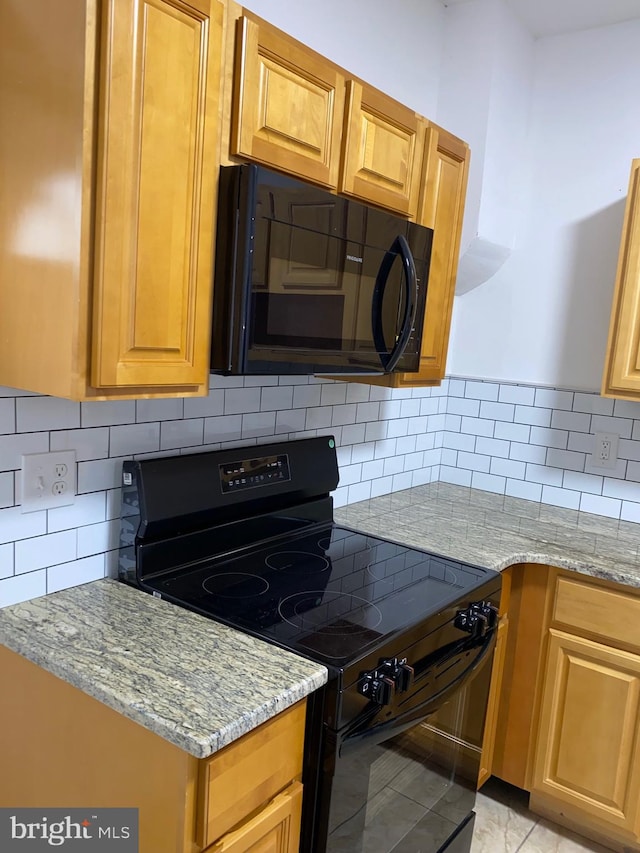 kitchen featuring black appliances, decorative backsplash, and light stone countertops