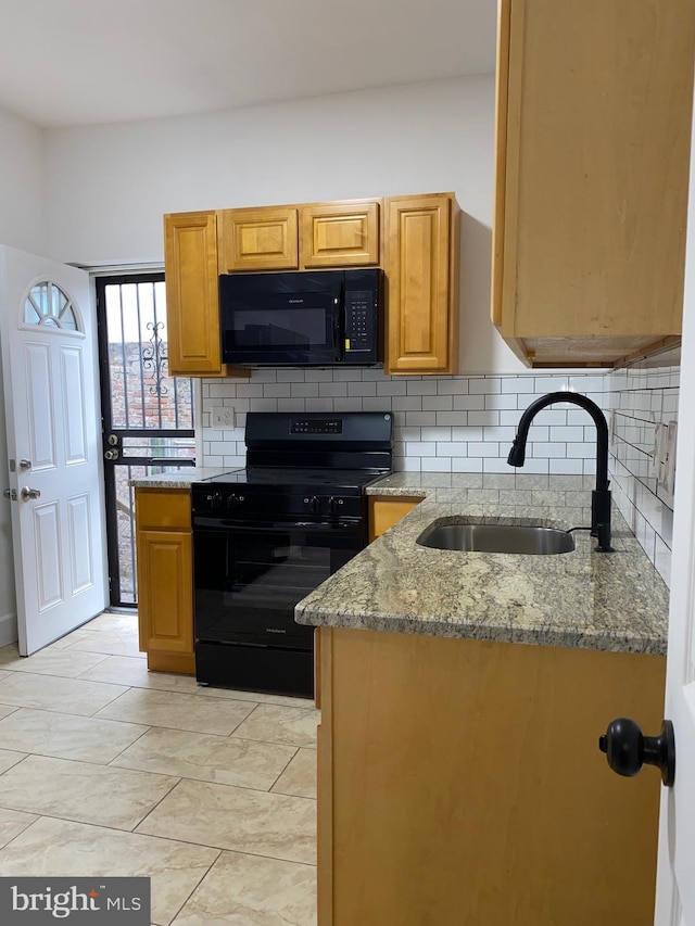 kitchen featuring light stone counters, decorative backsplash, brown cabinetry, a sink, and black appliances