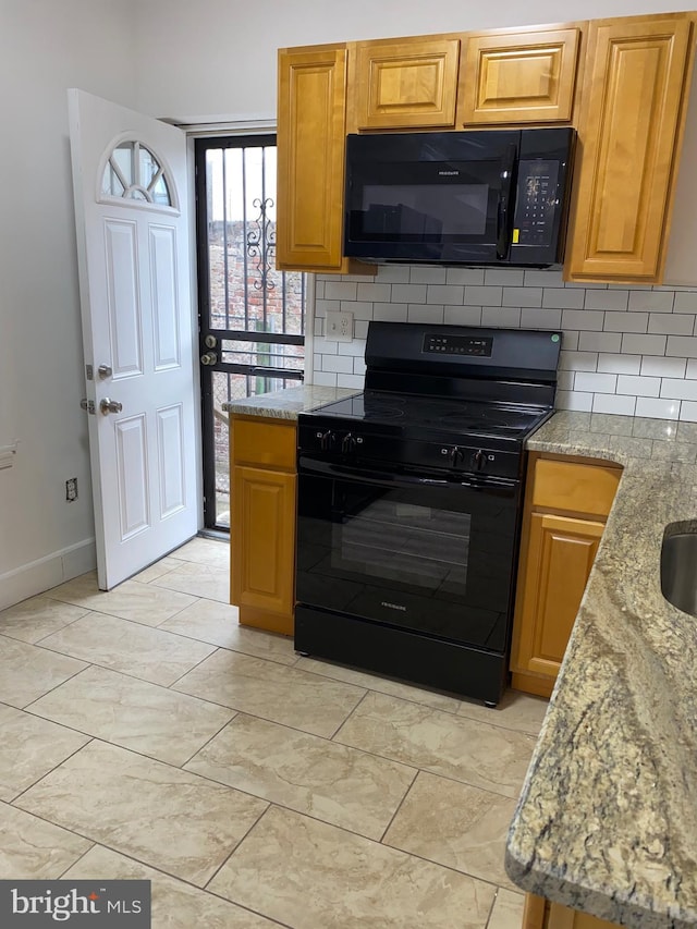 kitchen with baseboards, black appliances, backsplash, and light stone countertops