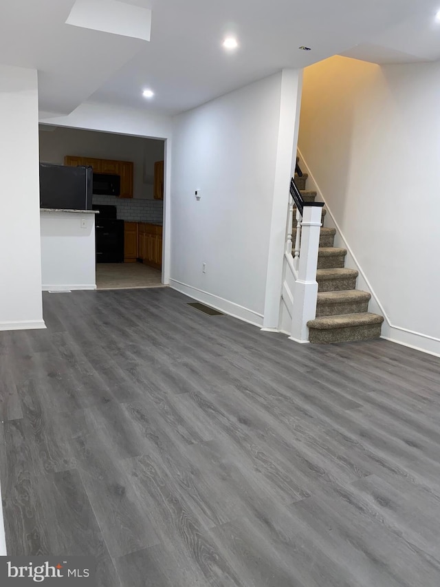 unfurnished living room with visible vents, baseboards, dark wood-style flooring, stairs, and recessed lighting