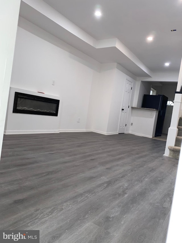 unfurnished living room with stairs, recessed lighting, a glass covered fireplace, and baseboards