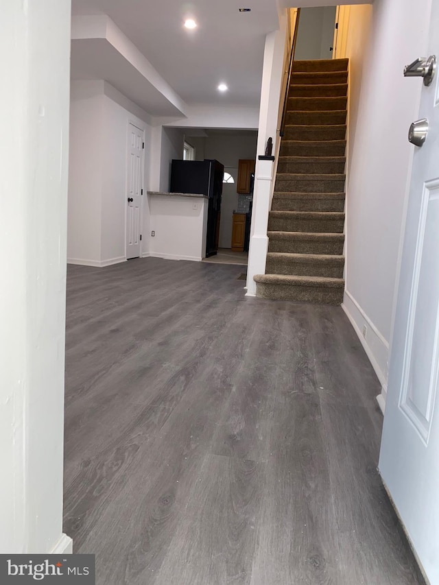 unfurnished living room with stairway, recessed lighting, dark wood finished floors, and baseboards