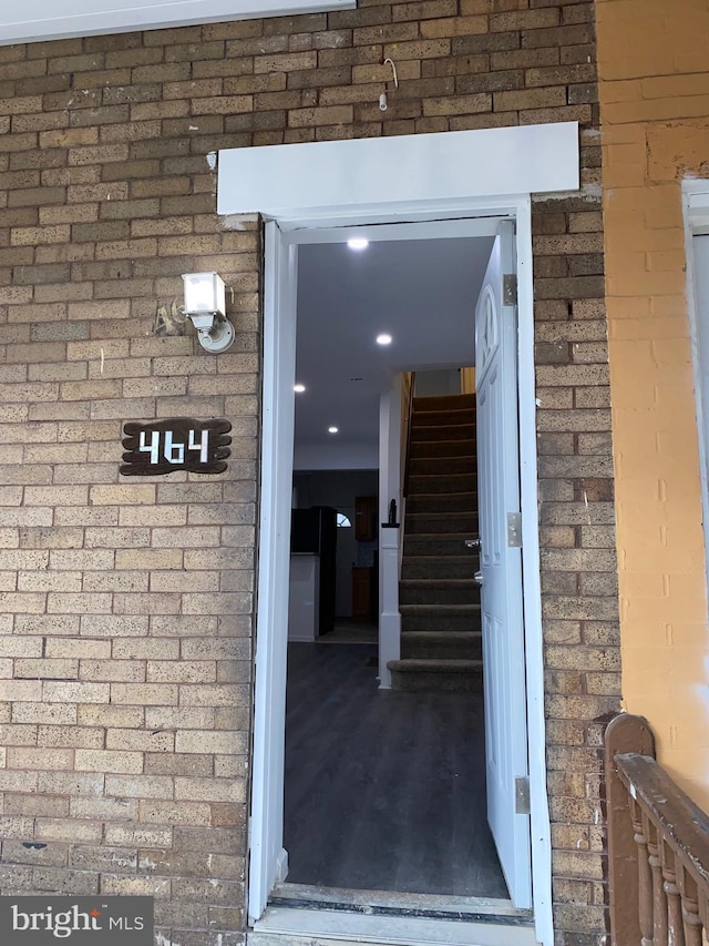 doorway to property with roof with shingles and brick siding