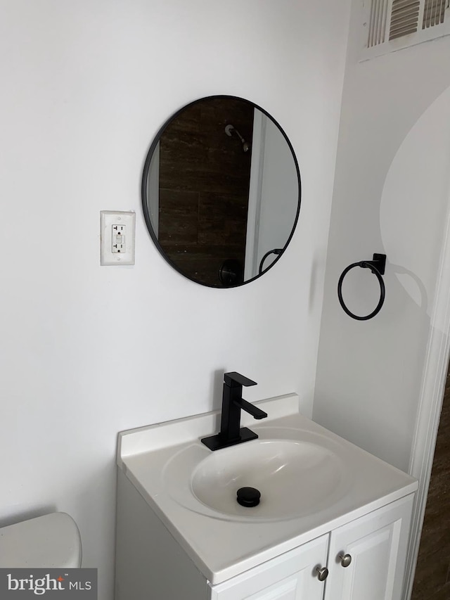 bathroom with toilet, vanity, and visible vents