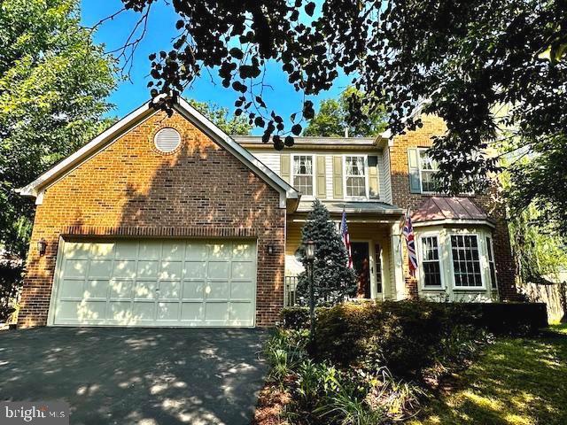 traditional-style home featuring aphalt driveway, an attached garage, and brick siding