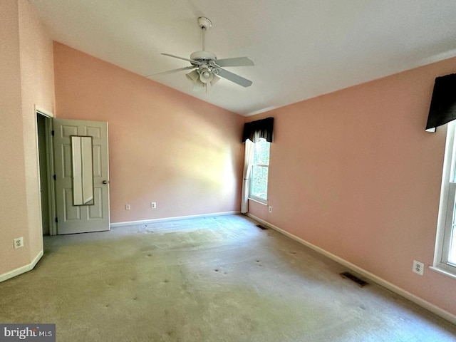 unfurnished room with baseboards, visible vents, carpet floors, lofted ceiling, and ceiling fan