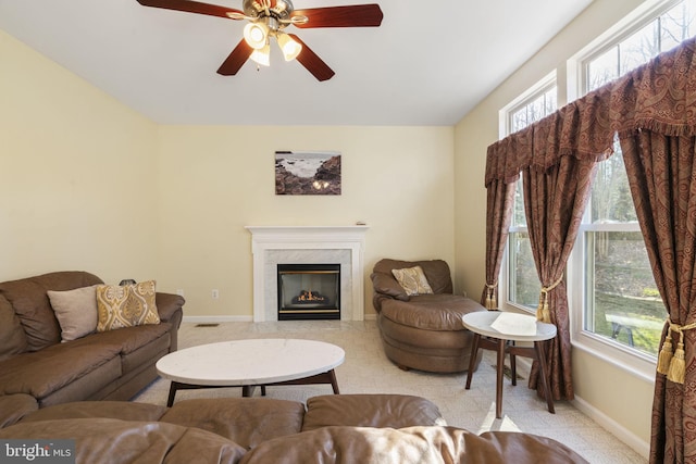 living room featuring a ceiling fan, visible vents, baseboards, and a premium fireplace