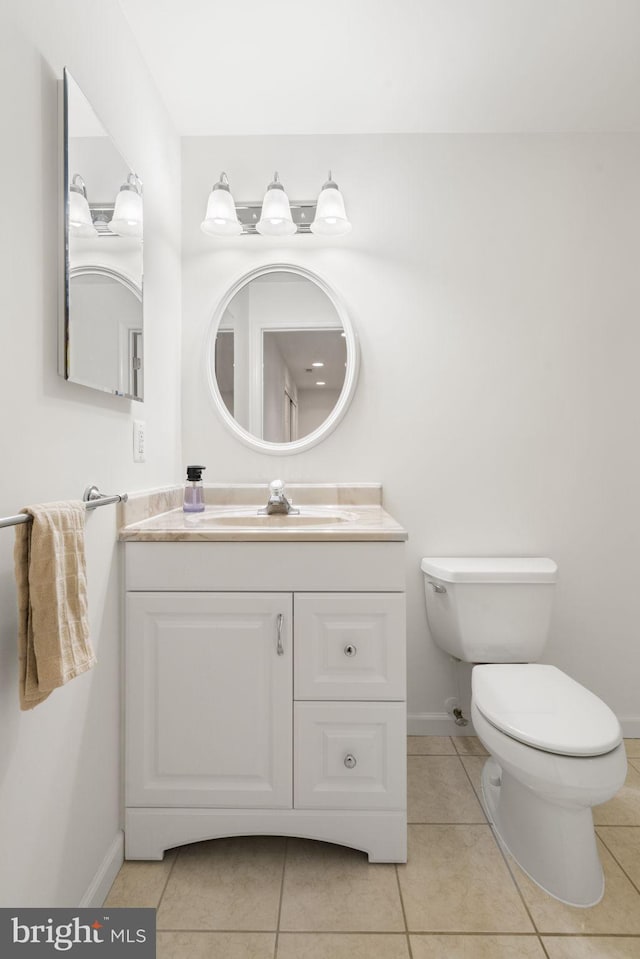 half bathroom featuring baseboards, toilet, vanity, and tile patterned flooring