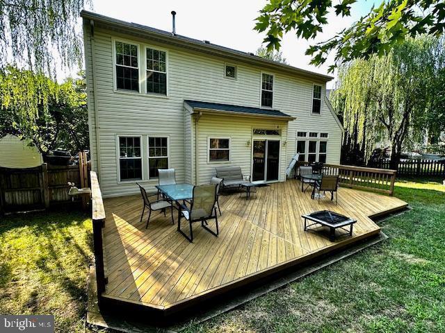 rear view of house featuring a yard, a deck, outdoor dining space, and fence