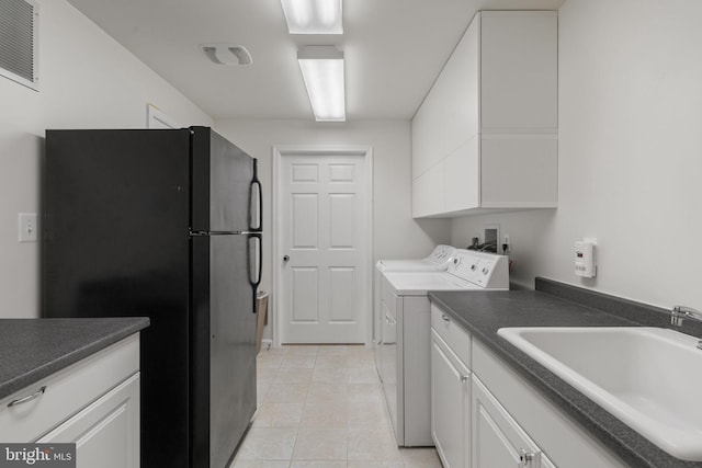 kitchen with white cabinetry, dark countertops, freestanding refrigerator, and a sink