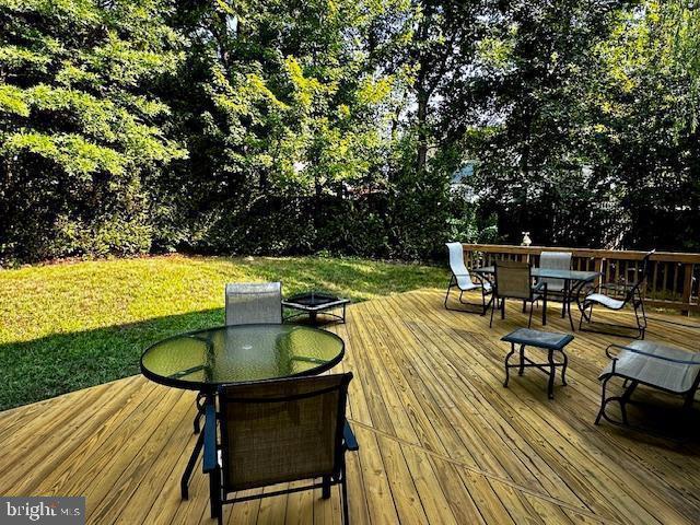 wooden terrace with outdoor dining area and a yard