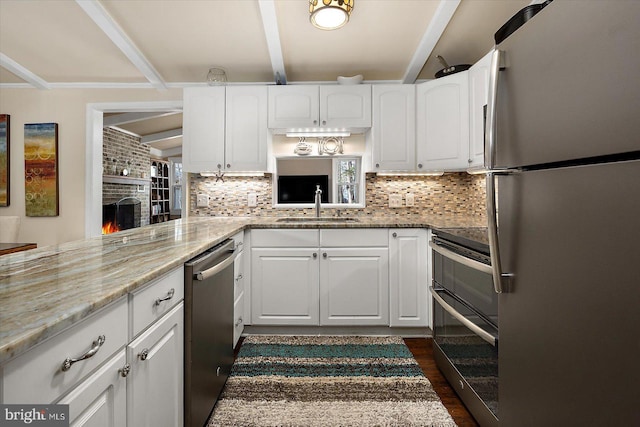 kitchen with a sink, decorative backsplash, appliances with stainless steel finishes, and white cabinetry