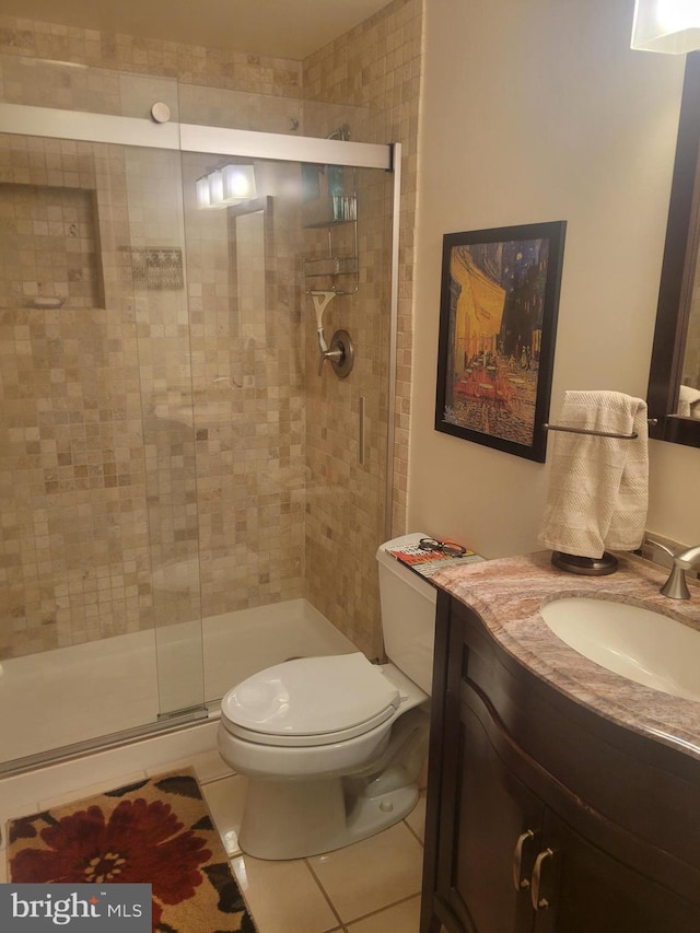 bathroom featuring tile patterned flooring, a stall shower, toilet, and vanity