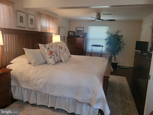 bedroom with wood finished floors, baseboards, visible vents, ceiling fan, and crown molding