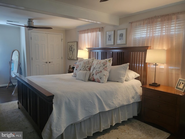 bedroom featuring wood finished floors, baseboards, beam ceiling, a closet, and crown molding