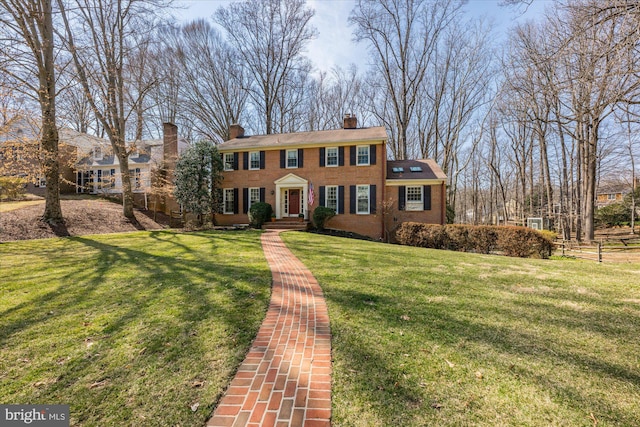 view of front of home featuring brick siding, a chimney, and a front lawn