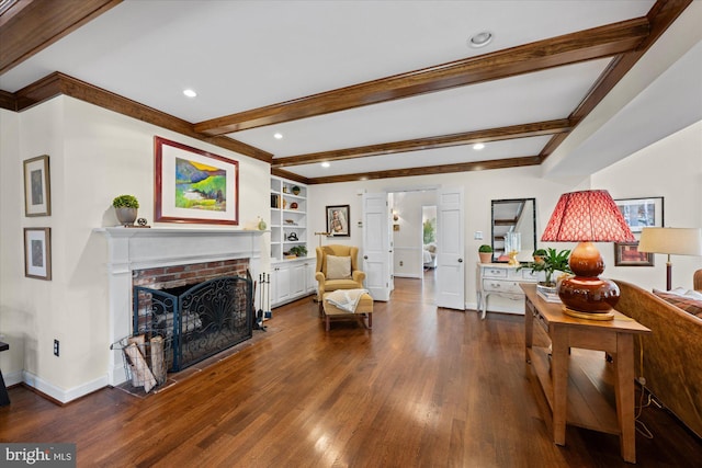 living room featuring beam ceiling, built in features, wood finished floors, baseboards, and a brick fireplace