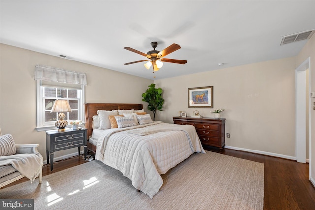 bedroom featuring a ceiling fan, dark wood-style floors, visible vents, and baseboards