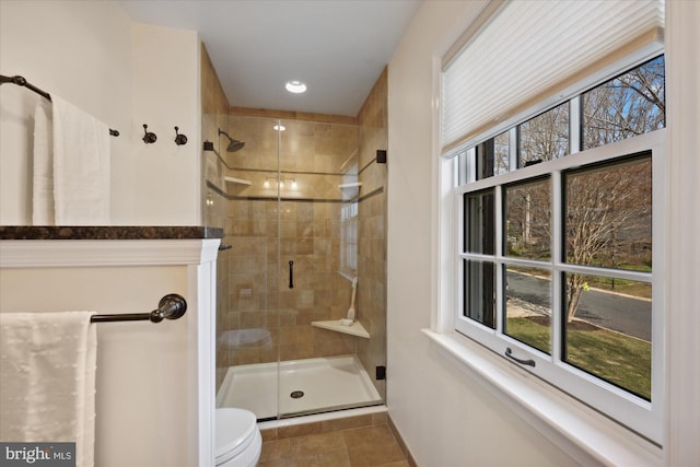 full bathroom featuring tile patterned floors, toilet, and a stall shower