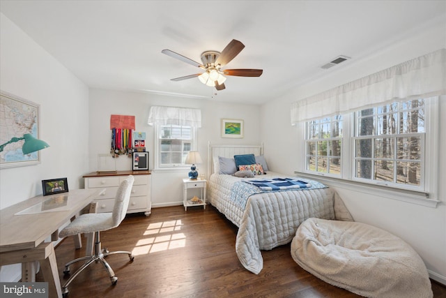 bedroom with ceiling fan, visible vents, baseboards, and wood finished floors