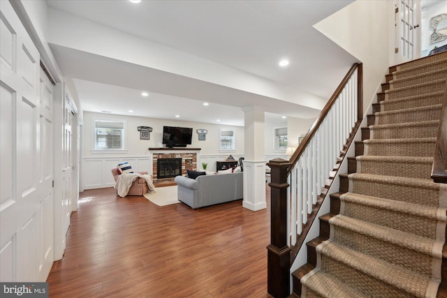 interior space featuring wood finished floors, a wainscoted wall, a fireplace, recessed lighting, and a decorative wall