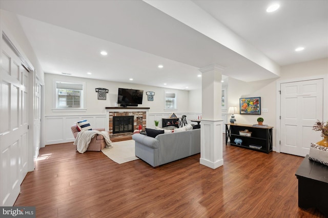 living area featuring recessed lighting, wood finished floors, a fireplace, and ornate columns