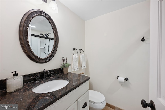 bathroom with toilet, vanity, and baseboards