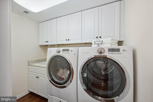 washroom featuring visible vents, baseboards, cabinet space, independent washer and dryer, and dark wood-style flooring