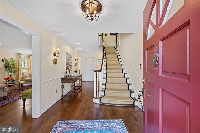 foyer entrance with dark wood-style floors, stairs, an inviting chandelier, and ornamental molding