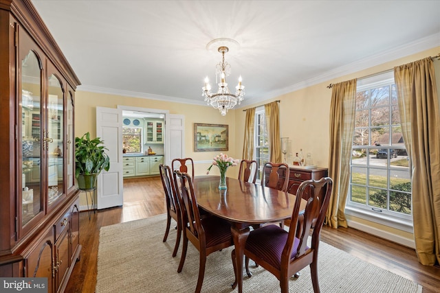 dining area with an inviting chandelier, dark wood-style floors, and crown molding