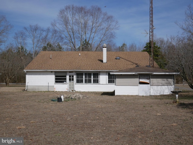 rear view of house with roof with shingles and a chimney