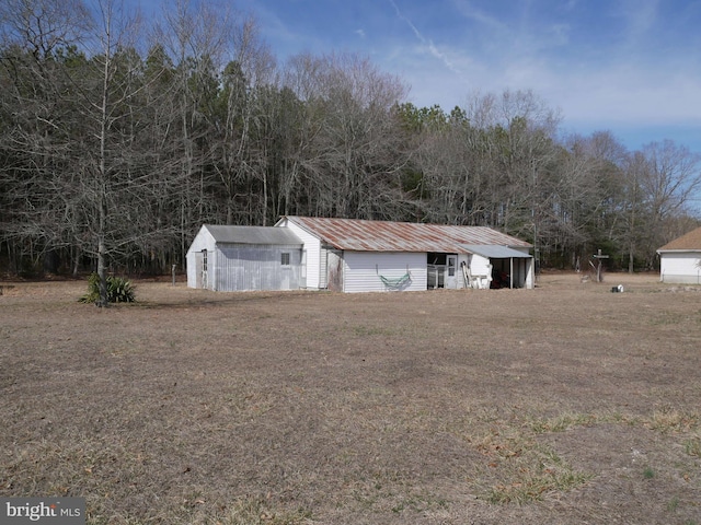 exterior space with an outbuilding, a front lawn, and metal roof