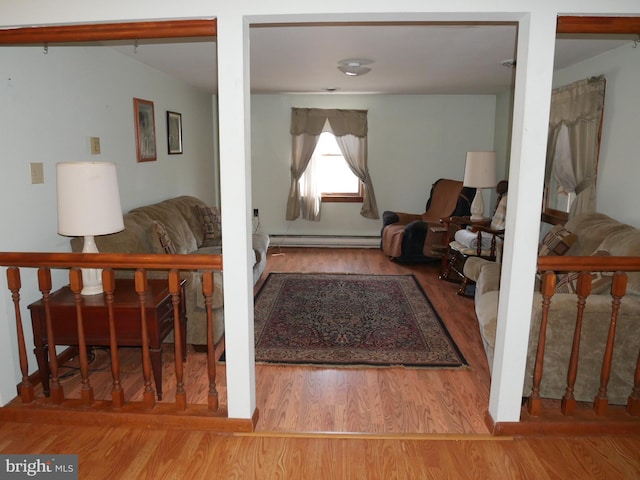 interior space with a baseboard heating unit and wood finished floors