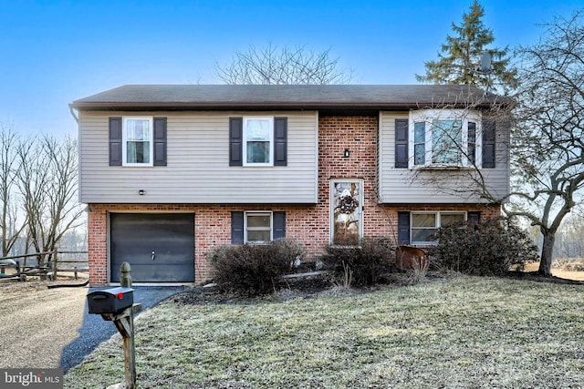 split foyer home featuring brick siding, a front yard, an attached garage, and aphalt driveway