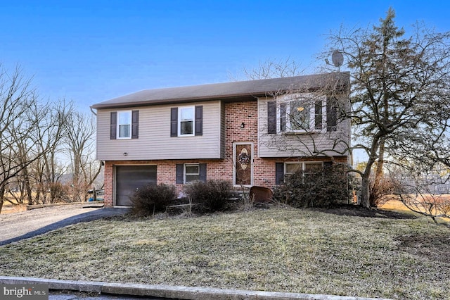 split foyer home with brick siding, driveway, and an attached garage