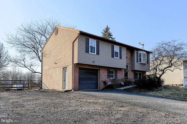 view of front of property with a garage, fence, aphalt driveway, and brick siding