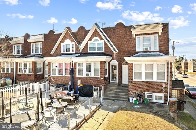 townhome / multi-family property featuring entry steps, cooling unit, fence, and brick siding