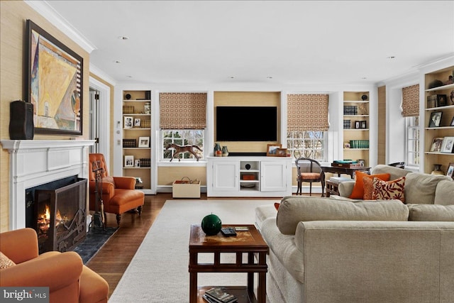 living room featuring a fireplace with flush hearth, dark wood-type flooring, built in shelves, and ornamental molding