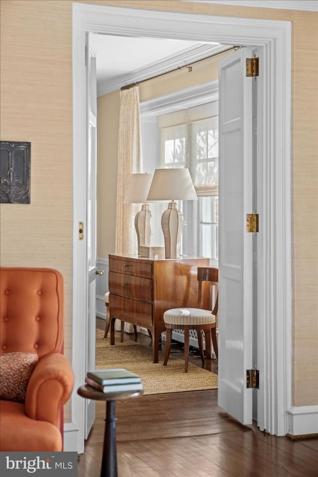 sitting room with wallpapered walls, crown molding, wood finished floors, and baseboards