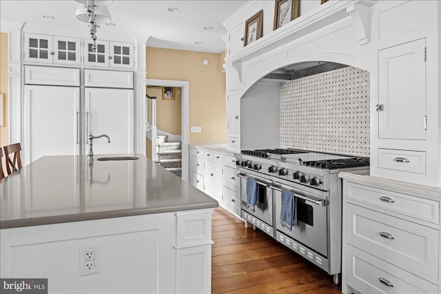 kitchen featuring tasteful backsplash, glass insert cabinets, double oven range, white cabinetry, and a sink