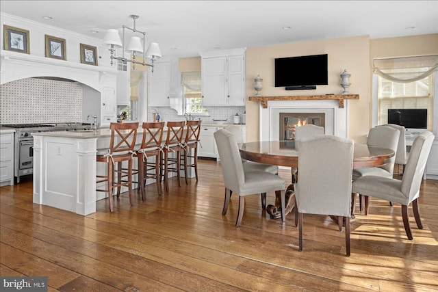 dining area with a notable chandelier, a glass covered fireplace, and hardwood / wood-style flooring