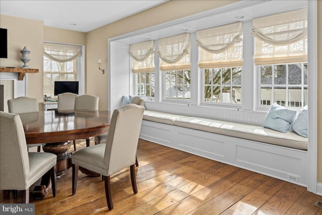 dining room featuring light wood-style flooring, a fireplace, and a healthy amount of sunlight