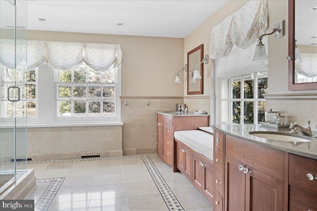 full bathroom with two vanities, a sink, wainscoting, tile patterned floors, and a shower with door