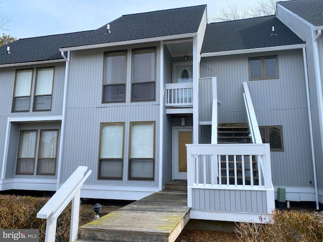 exterior space featuring roof with shingles and stairway