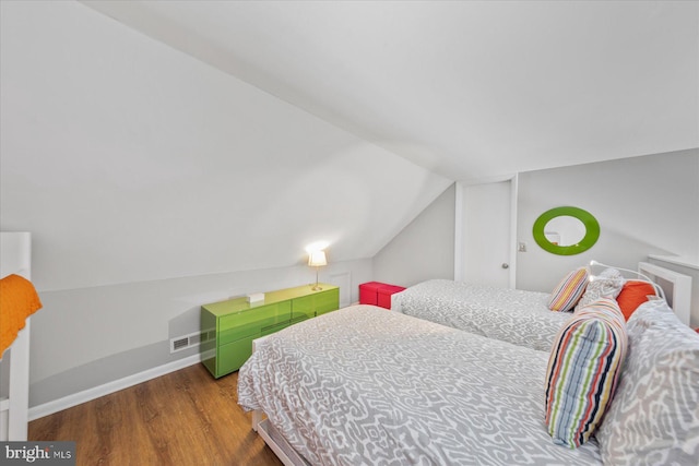 bedroom featuring lofted ceiling, baseboards, and wood finished floors