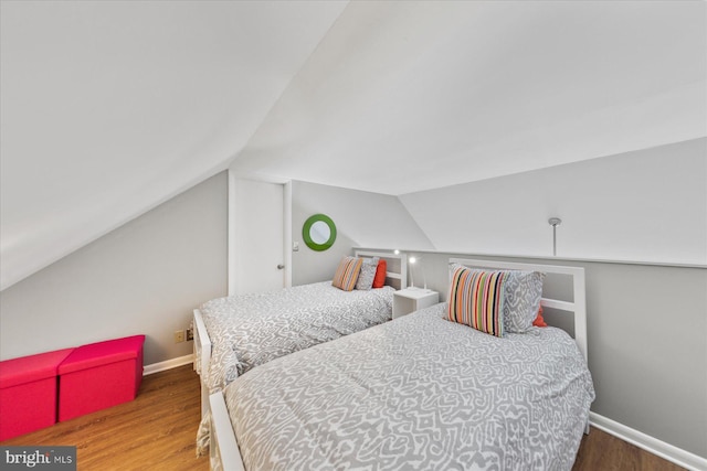 bedroom with lofted ceiling, wood finished floors, and baseboards