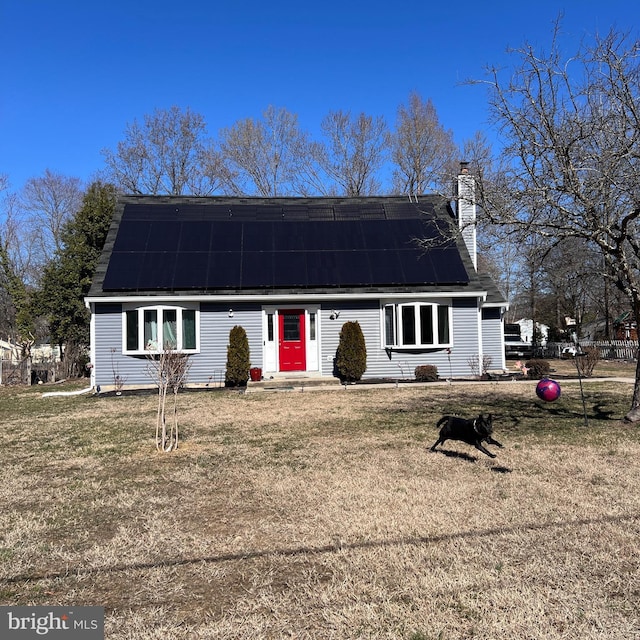 view of front of property with a chimney, solar panels, and a front yard