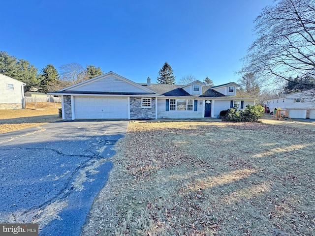 view of front facade with driveway, stone siding, a garage, and a chimney