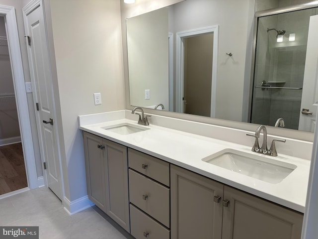 bathroom featuring double vanity, a spacious closet, a stall shower, and a sink