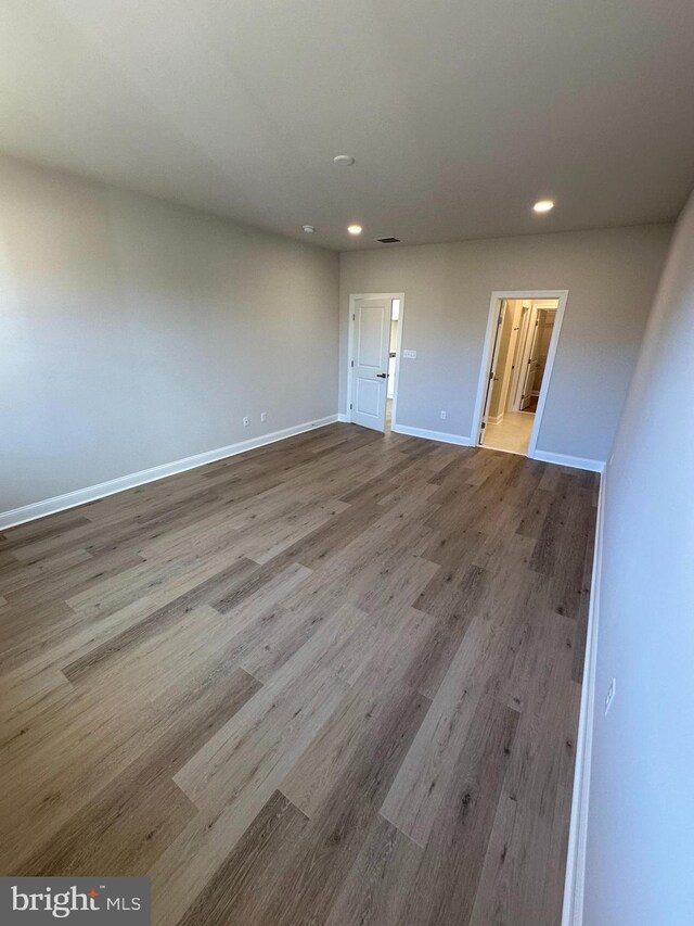 empty room featuring recessed lighting, wood finished floors, visible vents, and baseboards